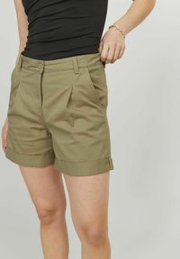 Pantaloni corti verde oliva in cotone, con orlo arrotolato, pieghe frontali e tasche laterali. La vita presenta una chiusura con bottone.