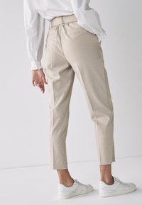 Beige geruite broek met een aansluitende pasvorm, elastische taille en enkellange snit, gecombineerd met witte sneakers. Getextureerde stof.