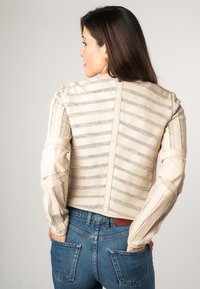 Giacca in pelle beige con strisce verticali e maniche strutturate. Design corto con cuciture dettagliate e una silhouette aderente.