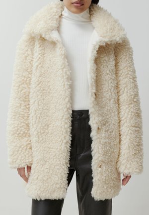 Crème-kleurige faux fur jas met een gestructureerde, fluffy oppervlakte, grote kraag en knoopsluitingen, gecombineerd met een geribbelde witte coltrui.