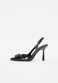 Sorte patent lær slingback pumpe med spiss tå, som har en glanset finish og en spenne detalj foran. Stiletthæl.