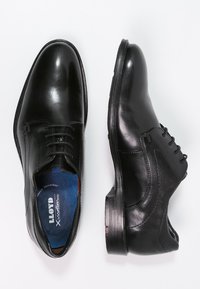 Scarpe da uomo in pelle nera con finitura liscia, punta tondeggiante, design con lacci e soletta blu etichettata "ammortizzatore." Suole in gomma.