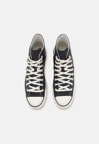 Zapatillas altas en textil azul marino con suelas de goma blancas. Las características incluyen cordones blancos, detalles de hardware plateado y un acabado texturizado.