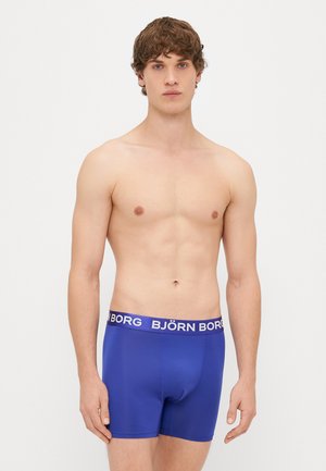Kék boxer alsóneműk, puha textúrával, fehér elasztikus derékpánttal, amelyen vastag betűkkel olvasható a "BJÖRN BORG" felirat.