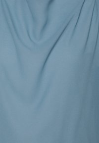 Lichtblauwe stof met een gladde textuur, die zich zacht laat draperen en subtiele plooien vertoont, wat wijst op het zachte en vloeiende materiaal.