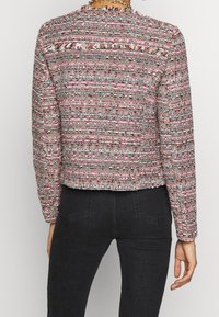 Tekstureret, flerfarvet blazer i pink, hvid og grøn med cropped design og frynser bagpå. Lange ærmer med tætsiddende form.