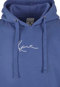 Felpa blu con cappuccio e coulisse con estremità in argento. Presenta un logo ricamato bianco sul petto. Tessuto in cotone morbido, vestibilità rilassata.