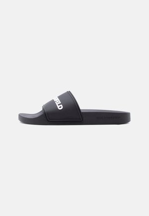 Black slide sandal with white text on the strap and embossed branding on the side, shown on a white background.