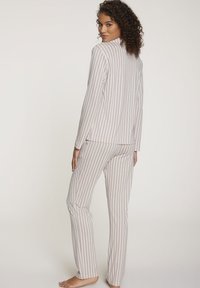Gestreepte pyjam sets in lichte stof, met verticale lijnen in zachte pastelkleuren. Langsleeve top en broek met een relaxed fit.