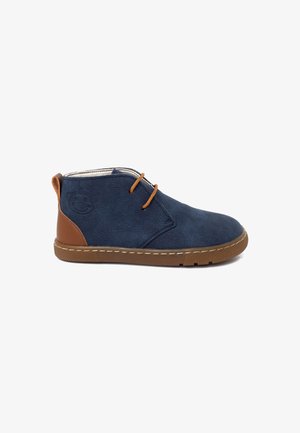 Navy blue suede ankle boots with brown leather accent, round toe, two brown laces, and light brown rubber sole. Features a monkey logo.