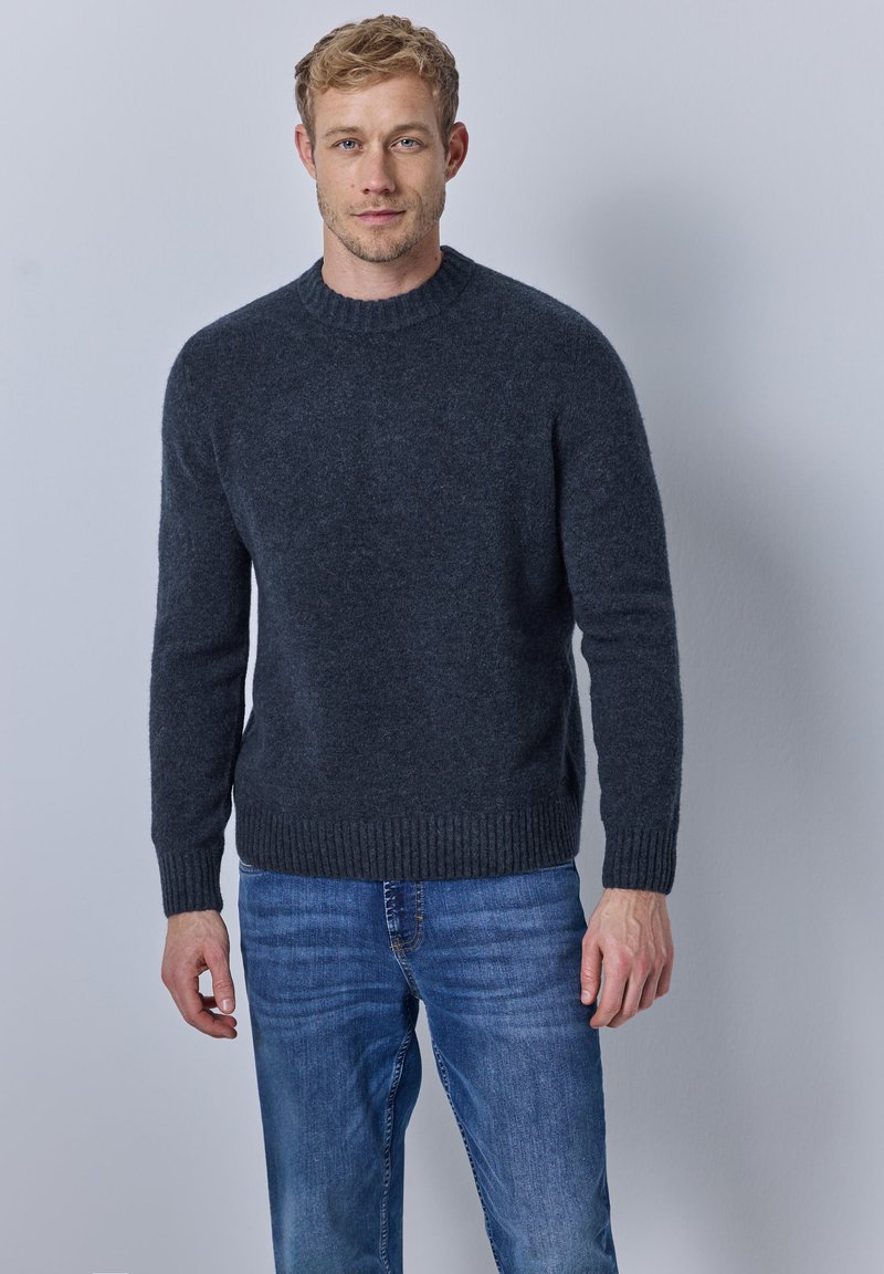 Dunkelgrauer Strickpullover mit rundem Halsausschnitt, gerippten Bündchen und Saum, kombiniert mit blauen Jeans. Glatte Textur, mittelschwerer Stoff.