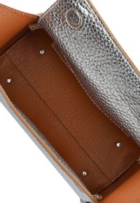 Zilverkleurige leren portemonnee met een gestructureerde textuur en een gladde bruine binnenkant, voorzien van een metalen drukknoop en studs voor sluiting, en afgeronde hoeken.