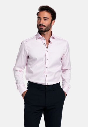 Lichtroze overhemd met een spread collar, zilveren knopen en lange mouwen, gecombineerd met donkere broeken. Gladde stofstructuur.