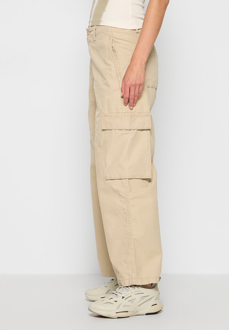 Pantalones cargo beige con un ajuste relajado, que cuentan con dos grandes bolsillos laterales, una tela de textura suave y detalles de costura sutiles.