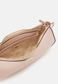 Lyserød syntetisk håndtaske med guldlynlås, indvendig lomme og foret med stof med gentaget "GUESS"-logo i en neutral nuance.