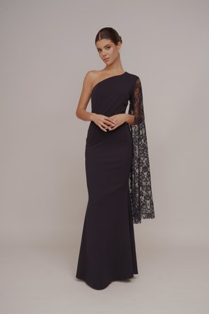 Navy blue muokkaava iltapuku, jossa on yksi olkahihna. Vasemmassa kädessä on läpinäkyvä pitsihihna, joka lisää tekstuuria ja monimutkaisia yksityiskohtia.