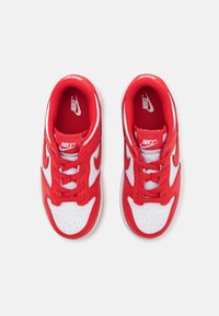 Červené a biele tenisky Nike s horným materiálom z textilu a syntetiky, okrúhla špička, šnurovanie, perforované detaily a gumová podrážka.