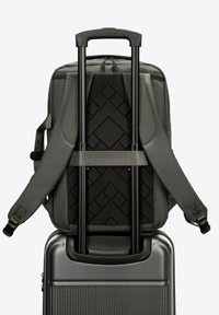 Grijze rugzak met verstelbare banden ligt op een zilveren hardcase-koffer. De koffer heeft een gestructureerd oppervlak en een uitschuifbare handgreep.