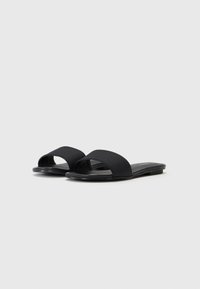 Svarta slidesandaler med en texturerad ovandel, öppen tå-design och platt sula, med en minimalistisk stil och slät finish.