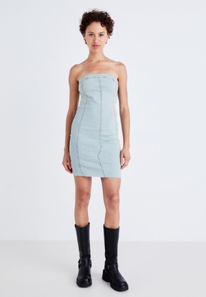Light blue denim strapless mini dress with vertical seams and frayed hem, paired with black knee-high boots featuring buckled accents.