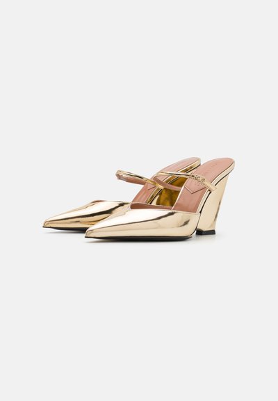 Tacones slingback metálicos dorados con puntera afilada, una correa delgada sobre el empeine y un diseño de tacón en cuña distintivo.