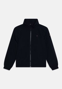 Black zip-up jacket with a high collar, elastic cuffs, side pockets, and small red, white, and blue logo on chest and sleeve.