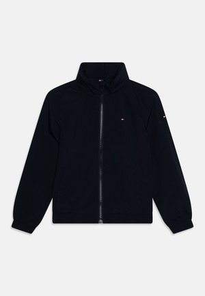 Zwarte zip-up jas met een hoge kraag, elastische boorden, zijzakken en een klein rood, wit en blauw logo op de borst en mouw.
