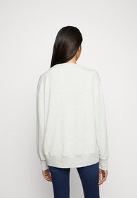 Sweatshirt gris à coupe décontractée, encolure large, et poignets et ourlet côtelés. Texture lisse, détails minimalistes, et style légèrement surdimensionné.