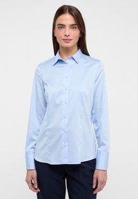 Camicia a maniche lunghe di colore azzurro chiaro realizzata in tessuto morbido, con chiusura a bottoni, colletto e vestibilità slim.