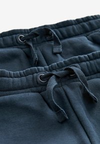 Mörkblåa sweatpants har en elastisk midja med dragsko, öljetter och ett mjukt vävt material. Designen inkluderar samlad sömnad.