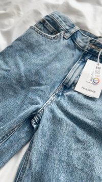 Svijetloplave traperice s blago izblijedjelom teksturom, s patentnim zatvaračem, dizajnom s pet džepova i pričvršćenom oznakom marke.