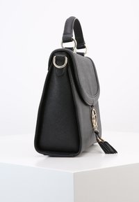 Svart strukturerad läderhandväska med textur. Har en framflik, silverfärgad hårdvara och ett dekorativt snör-ackcent.