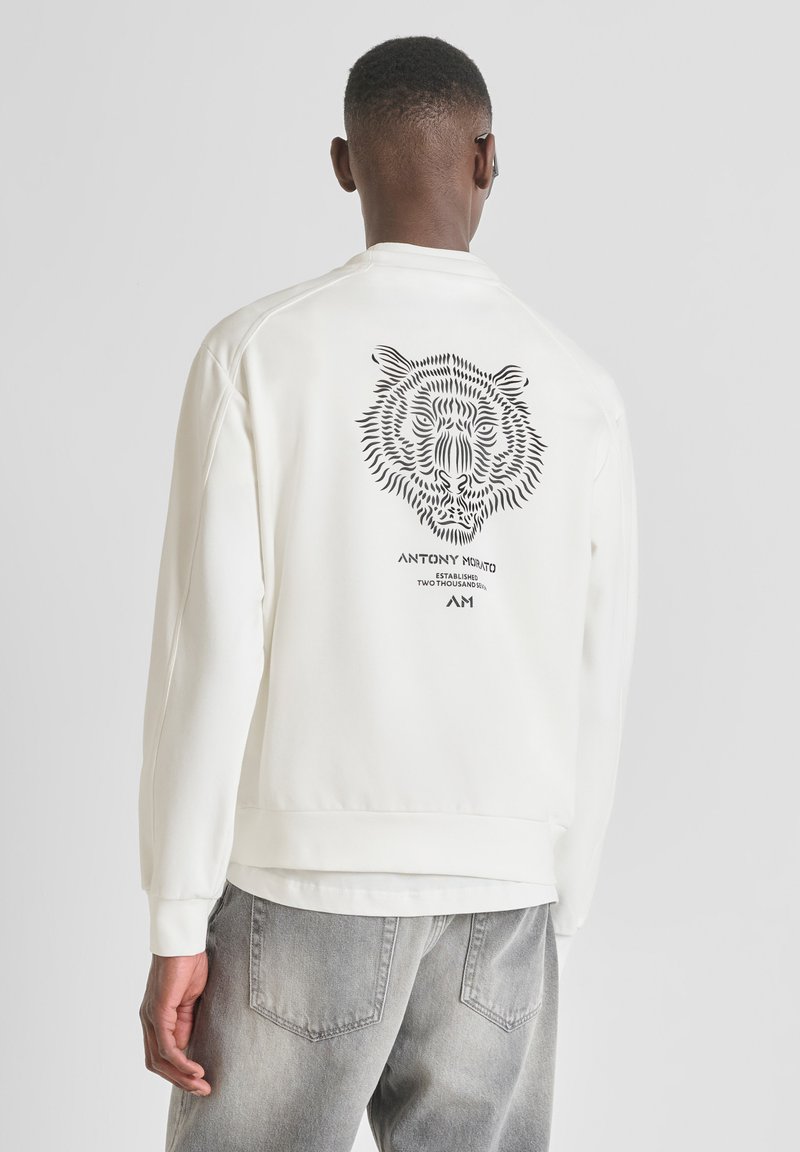 Sudadera de algodón blanca con un gráfico de tigre negro en la espalda, puños y dobladillo acanalados, corte relajado y cuello de tripulación.