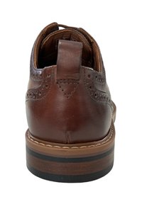 Zapato de cuero marrón con diseño de brochado, que presenta una textura suave, suela oscura con un ligero contraste y un tirador en la parte trasera.