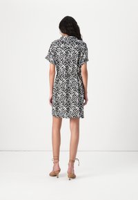 Φόρεμα κοντό μανίκι με αφηρημένο σχέδιο φύλλων σε άσπρο και μαύρο χρώμα; τσιτωμένη μέση, μήκους μέχρι το γόνατο, από ελαφρύ ύφασμα. Υποδήματα με λουράκια σε ουδέτερους τόνους.