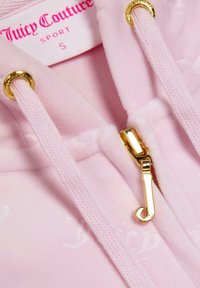 Világos rózsaszín velúr kapucnis felső arany cipzárral, elülső zsebből és húzózsinórból. A címke "Juicy Couture SPORT" felirattal rendelkezik élénk rózsaszín színben.