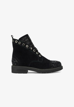 Schwarze Wildleder-Stiefeletten mit einem strukturierten schwarzen Panel, Nieten, Metall-Ösen und einer flachen Sohle. Abgerundete Zehenpartie mit dekorativen Akzenten.