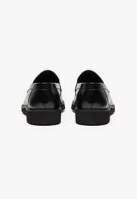 Chaussures décontractées en cuir noir avec une finition lisse, de forme arrondie et semelle en caoutchouc basse. Présentent un design minimaliste et des bords arrondis.