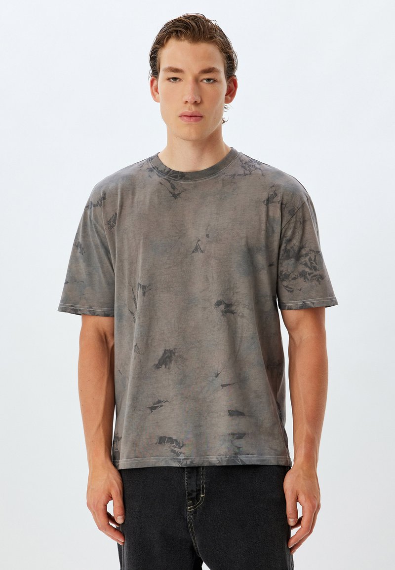 Grå tie-dye t-shirt med korte ærmer, rund halsudskæring og afslappet pasform. Blødt stof med et marmor mønster og lette teksturdetaljer.
