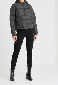 Polstret, cropped jakke i mørkegrå med lynlås foran, sidelommer og hætte. Sættes sammen med sorte leggings og skinnende ankelstøvler.