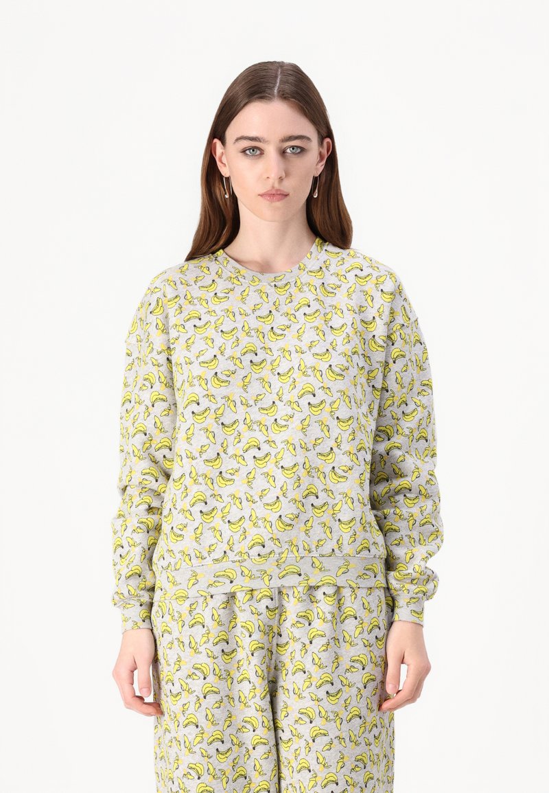 Camisola cinza com estampado de bananas, gola redonda, mangas longas e punhos canelados. Material suave com um corte relaxado e calças a condizer.