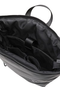 Bolsa de nylon negra con abertura con cremallera, presenta múltiples compartimentos y una correa para asegurar el contenido. Textura suave, diseño minimalista.
