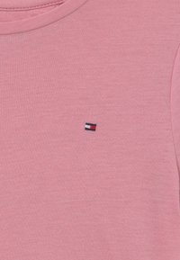 Pink bomulds T-shirt med rund hals. Har et lille broderet logo i rød, hvid og blå på venstre brystside. Glat tekstur.