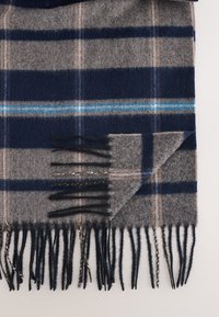 Vlněná šála s kostkovaným vzorem v námořnické modři, šedé a béžové barvě. Má třepení na okrajích, modrou zdobnou linku, jemnou texturu a obdélníkový tvar.