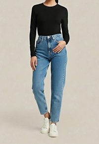 Czarna bluzka z długim rękawem zestawiona z wysokim stanem jasnoniebieskich dżinsów o prostych nogawkach, uzupełniona białymi trampkami.