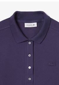 Polo shirt slim fit di colore viola realizzato in cotone texturizzato, con una pattina a due bottoni e un logo ricamato. Design del collo classico.