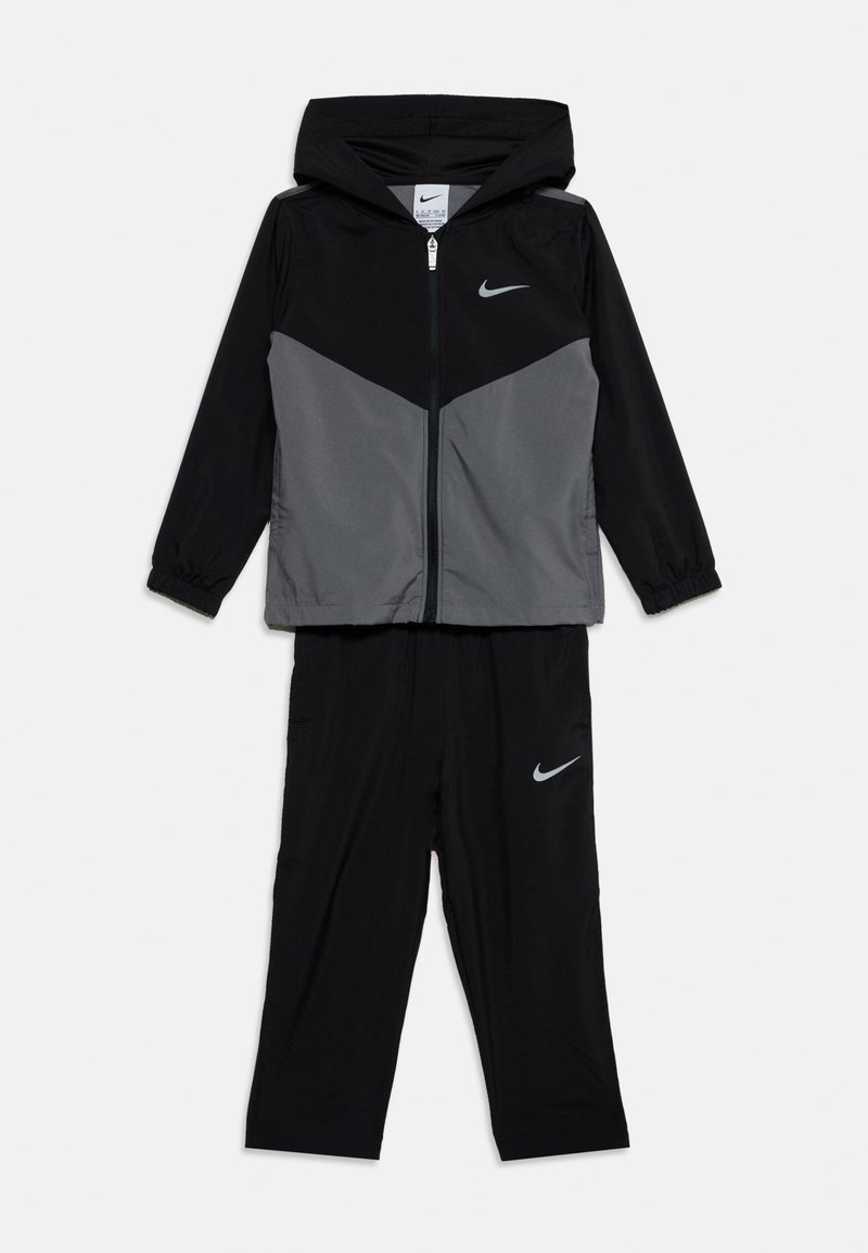 Μαύρο και γκρι μπουφάν Nike με κουκούλα και φερμουάρ και αντίστοιχο μαύρο παντελόνι, και τα δύο με λευκά λογότυπα Nike swoosh.