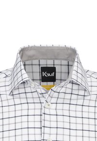 Camicia bianca con motivo a reticolo navy, colletto, apertura con bottoni e etichetta. Materiale in cotone con texture liscia; presenta cuciture e bottoni visibili.