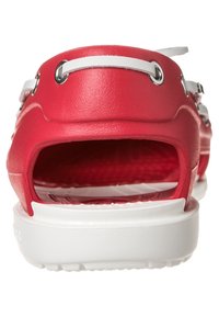 Sandale en caoutchouc rouge avec un semelle intérieure texturée, talon ouvert et détails de sangle blanche. Semelle plate avec de petites rainures pour une meilleure adhérence.