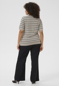 Gestreepte gebreide top in beige met zwart-witte strepen, korte mouwen en een ronde halslijn, gecombineerd met zwarte wijde broek.